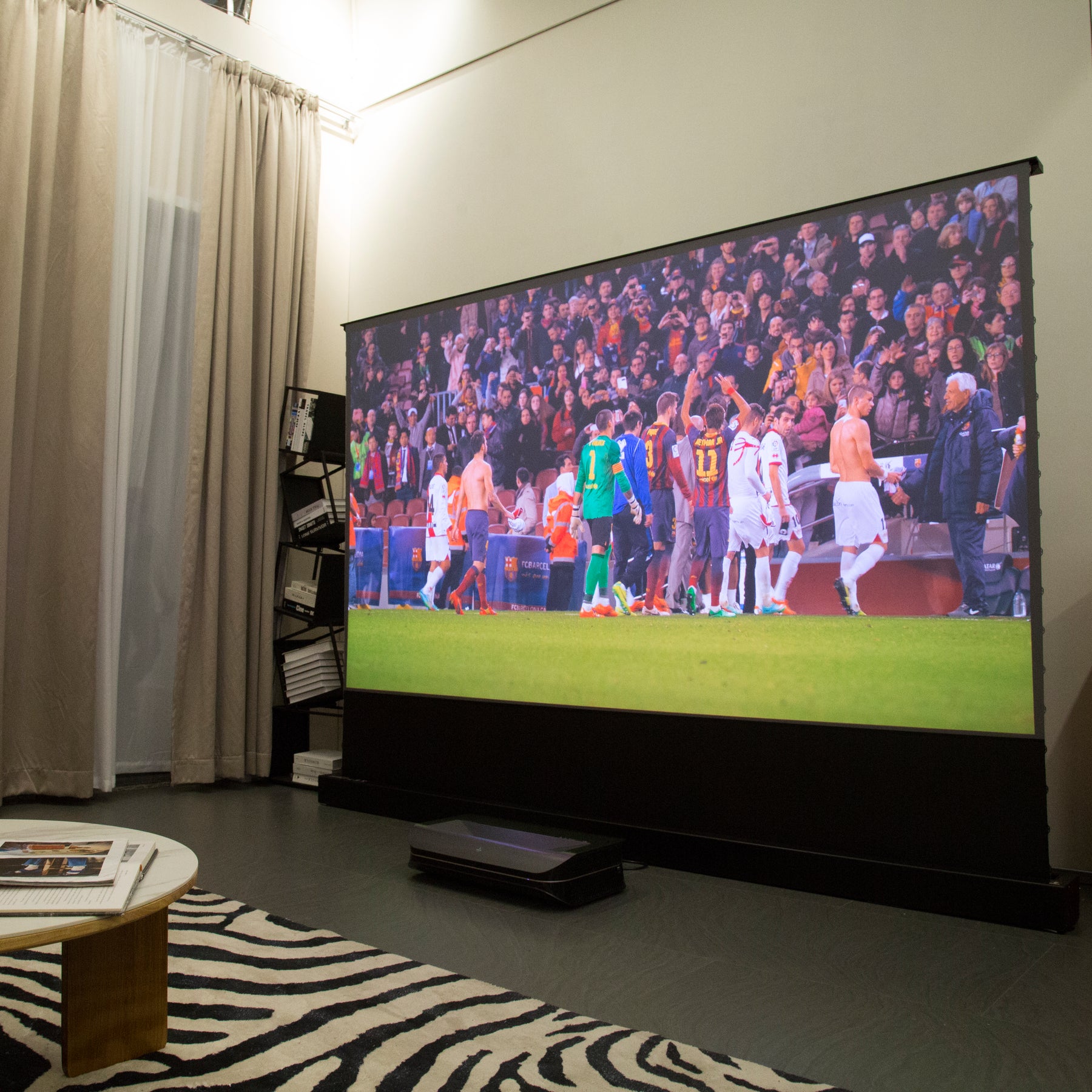 AWOL Vision projector enhances a sports watching experience with a soccer match displayed on a large screen, perfect for gathering with friends.
